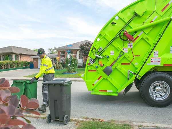 a waste collection employee loading a garbage truck